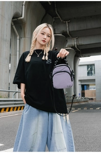 Détail d'un mini sac bandoulière violet en nylon avec double fermeture éclair et poignée