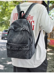 Outdoor shot of a vintage charcoal grey denim backpack with acid wash texture detail