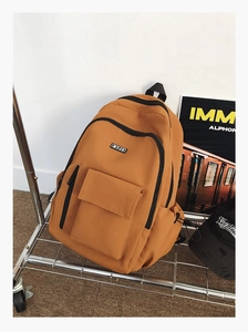 Detail of amber yellow canvas backpack with double front pockets and black zippers