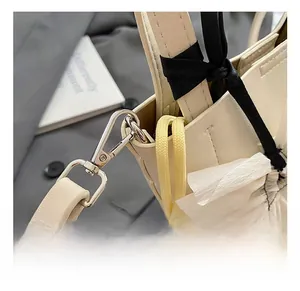 Détail du crochet en métal argenté et de la bandoulière sur le sac en cuir crème