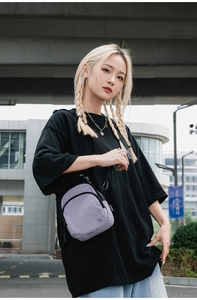 Détail d'un sac bandoulière en nylon violet avec double fermeture éclair et sangle