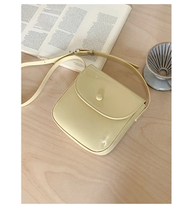 Vue détaillée du sac besace carré crème avec boucle ronde posé sur une table en bois