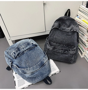 Close-up detail of vintage denim backpacks in light blue and dark grey with zip pockets