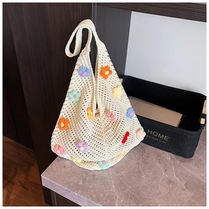 Détail d'un sac en tricot crème avec des fleurs en crochet 3D colorées et texture maille