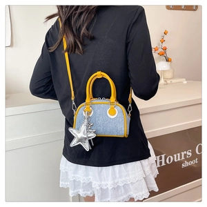 Detail of blue denim crossbody bag with yellow leather trim and silver star pendant