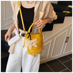 Détail du sac seau jaune ajouré avec pendentif floral et bandoulière amovible