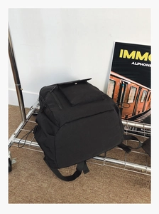 Detail showing high-quality black nylon backpack material and front flap pocket design