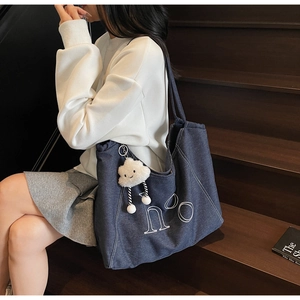 Detail of navy denim tote bag with h°o embroidery and plush cloud keychain accessory