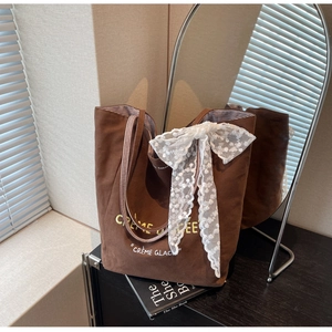 Detail of coffee brown canvas tote bag featuring lace bow and cream glacee print