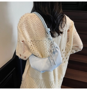Close-up of light blue crescent hobo bag with knotted strap and silver balloon dog charm