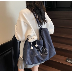 Detail of blue denim tote bag with white hoo letter print and fluffy cloud charm