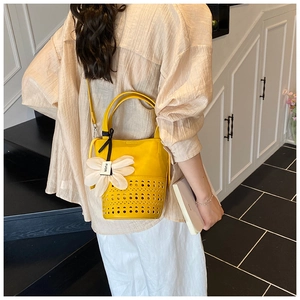 Détail du sac seau jaune ajouré avec bandoulière en cuir et grand pendentif fleur