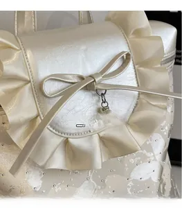 Close-up of elegant ruffles and bow detail on a white pearlescent commuter backpack