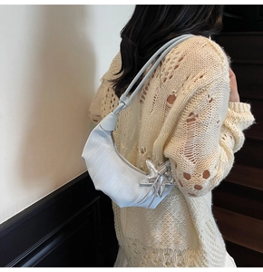 Light blue crescent bag with starfish charm shown styled with an ivory knit sweater