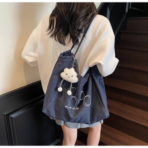 Detail of dark blue denim tote bag with white letter print and plush cloud charm on stairs