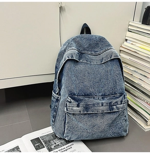 Close-up of washed blue denim backpack with zipper pockets and vintage texture