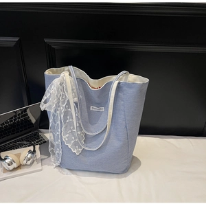 Detail of blue striped canvas tote featuring lace embroidery and Magic Pocket label