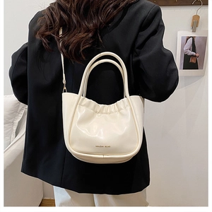 Detail of cream pleated bucket bag with cloud-style ruffles and ring handles