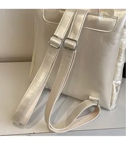 Detail of adjustable pearl white shoulder straps with silver metal buckles on backpack