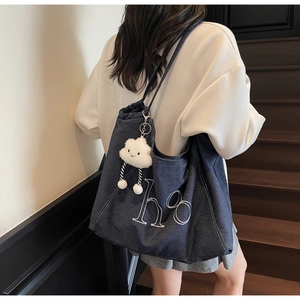 Detail of blue denim tote bag with white ho embroidery and cloud plush charm decoration