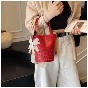 Détail du sac seau ajouré rouge avec doublure jaune à cordon et pendentif floral élégant