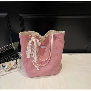 Detail of red striped canvas tote bag featuring EXKERT label and white lace decorative ribbon