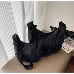Detailed view of black nylon dumpling bags in two sizes with adjustable wide straps