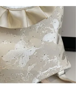 Macro detail of beige bow backpack with silk jacquard butterfly patterns and rhinestones