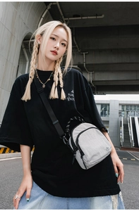 Détail du sac bandoulière en nylon imperméable avec double fermeture éclair et logo latéral