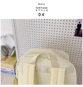 Detail of beige nylon backpack with reinforced handles on white pegboard backdrop