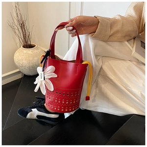 Détail du sac cabas rouge ajouré avec doublure jaune à cordon et pendentif fleur chic