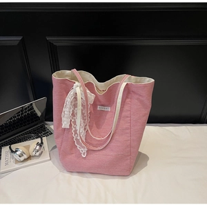 Close-up of red striped canvas tote bag with white lace bow and laptop lifestyle setting