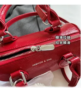 Vue rapprochée du sac à main cylindrique rouge avec fermeture éclair argentée et cuir