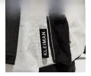 Detail view of the KLEIMAN brand label on a gray nylon backpack with clean stitching
