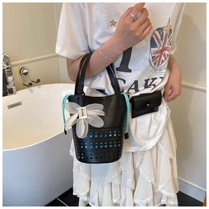 Détail du sac cabas ajouré noir avec breloque fleur blanche et cordons bleu ciel