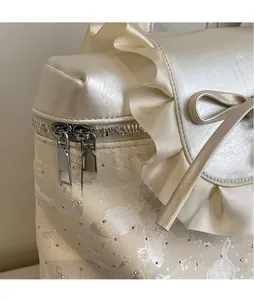 Close-up of smooth metal double zippers and ruffled bow detail on a cream white bag
