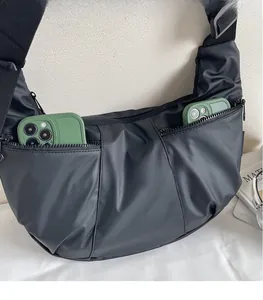 Detail of black crescent bag with two front zippers showing high capacity for two smartphones