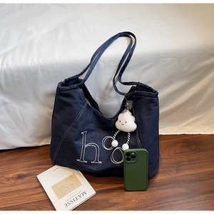 Detailed embroidery of letters on vintage dark blue denim tote bag with plush charm