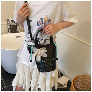 Détail du sac seau ajouré avec pendentif floral et cordon dans un décor de style de vie