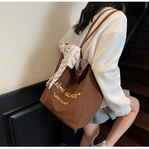Detail of a brown canvas tote bag with lace ribbon and Créme Glacée print detail