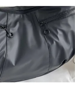 Detail of black nylon fabric texture and circular metal zipper pull on a casual shoulder bag