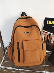 Vibrant orange backpack for students and travel on a metal shelf with art poster