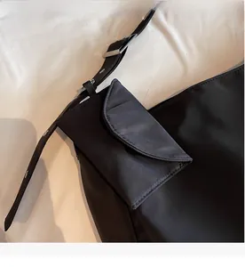Close-up of black nylon tote bag featuring detachable outer pocket and silver buckle