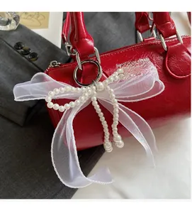 Détail du sac cylindre en cuir rouge avec nœud en organza et perles fantaisie