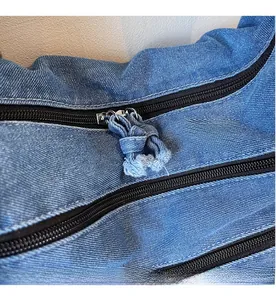 Close-up of smooth black zipper with denim knot puller on classic blue handbag