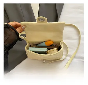 Detail showing internal capacity of cream quilted square bag with phone and makeup
