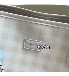 Close-up of beige plaid tote bag showing the MEIGEFI brand label and fine stitching