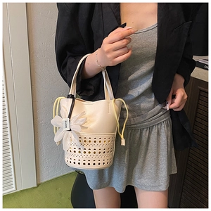 Détail du sac seau blanc crème avec motifs ajourés au laser et charm fleur décorative