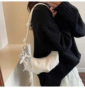 Detailed close-up of white crescent shoulder bag with silver star pendant and knot strap