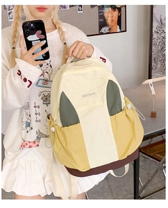 Detail shot of the nylon patchwork backpack showing side drawstring pockets and logo